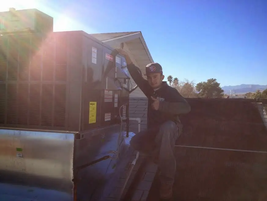 HVAC technician performing AC Tune-Up on a rooftop unit in Visalia